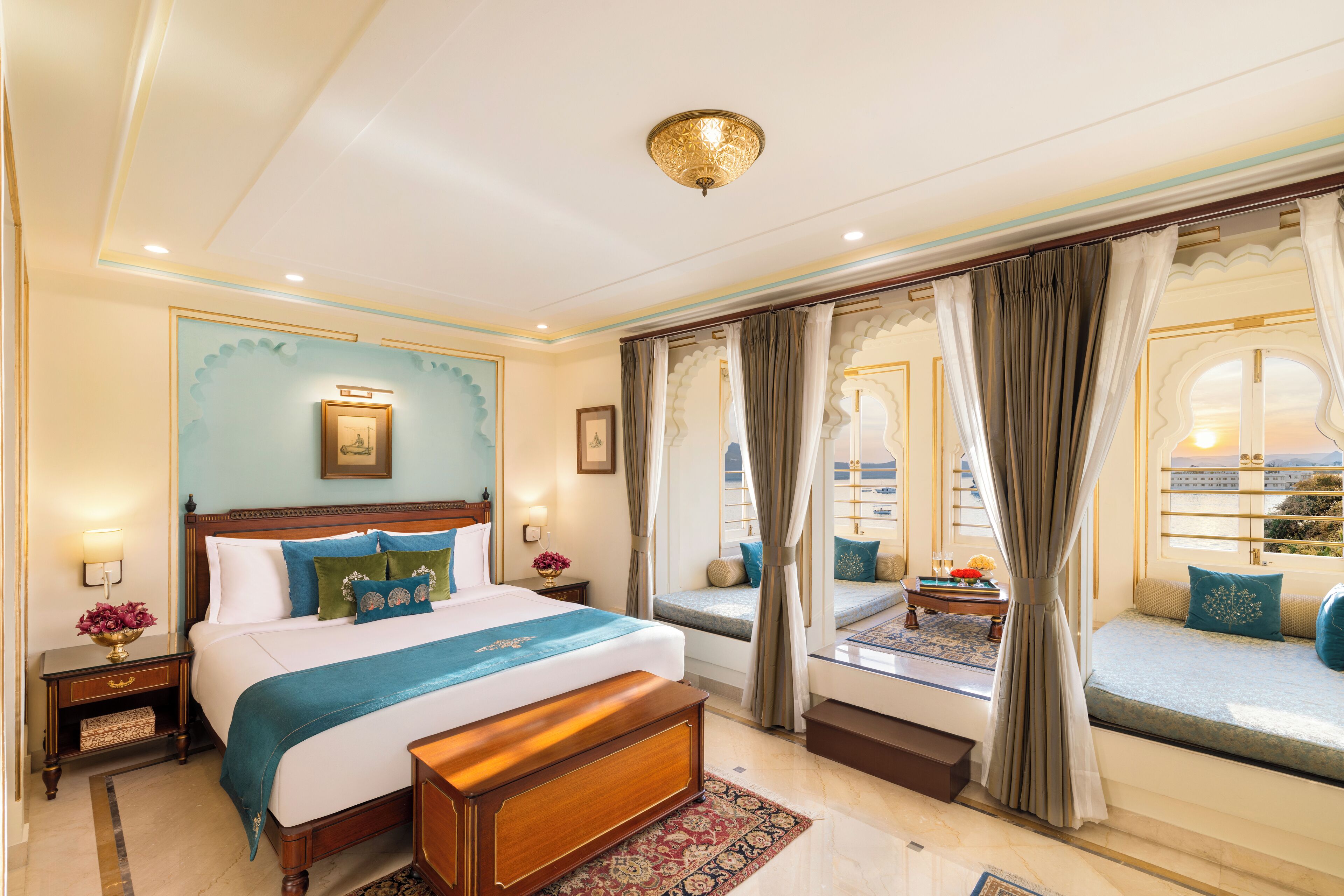 Um quarto espaçoso com uma cama grande, área de estar com vista e luminária decorativa no teto.