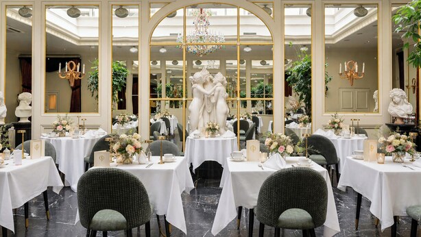 A formal dining room with tables set for service, a central statue, and classical decor. - Grand Palace Hotel – Small Luxury Hotels of the World (Riga)