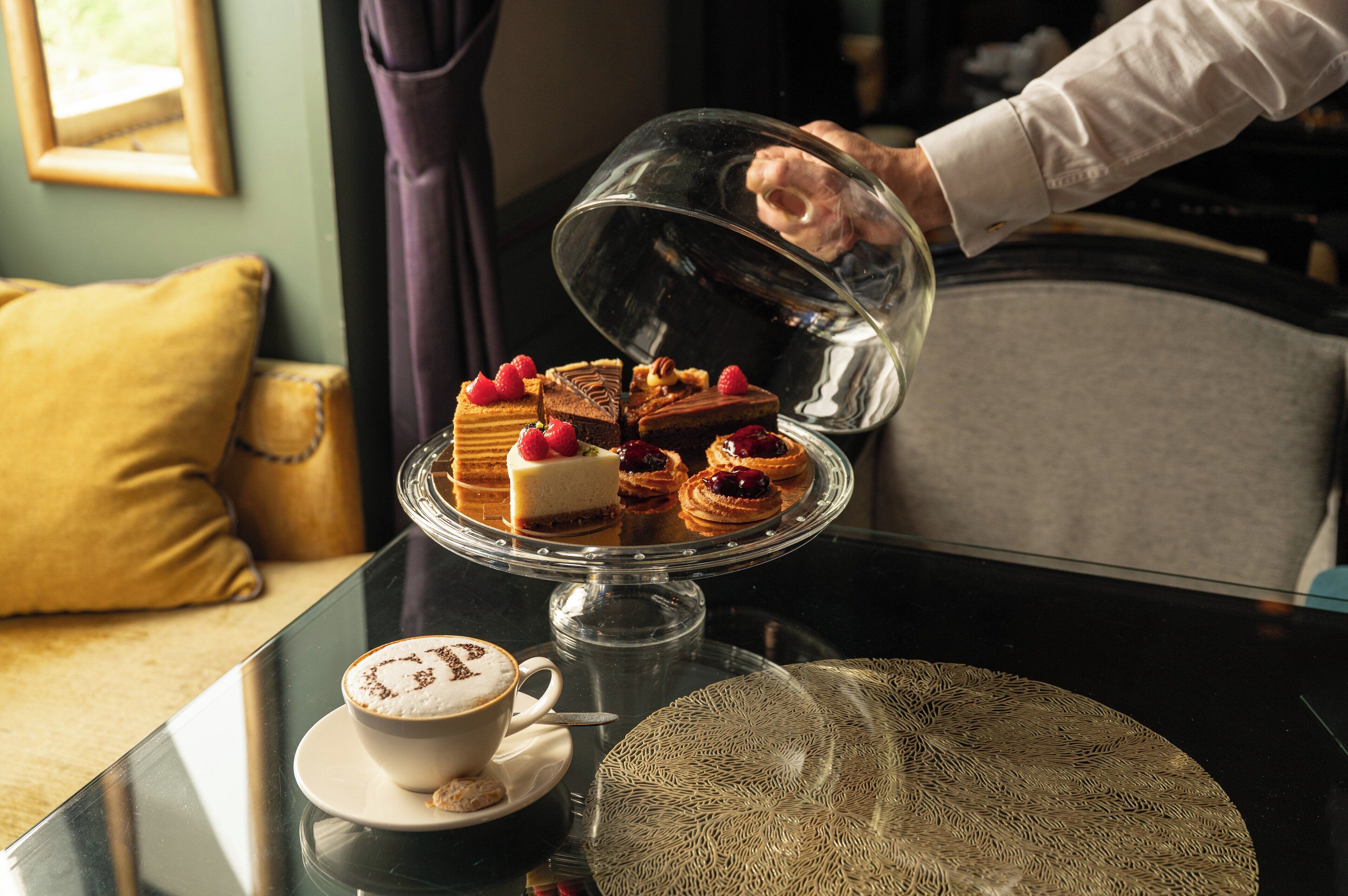 A dessert display with various pastries and a cup of coffee on a table.