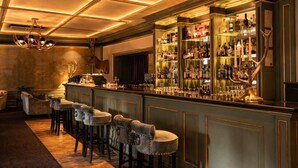 A bar area with a high bar counter, multiple stools, and a variety of bottles and glasses. - Grand Palace Hotel – Small Luxury Hotels of the World (Riga)