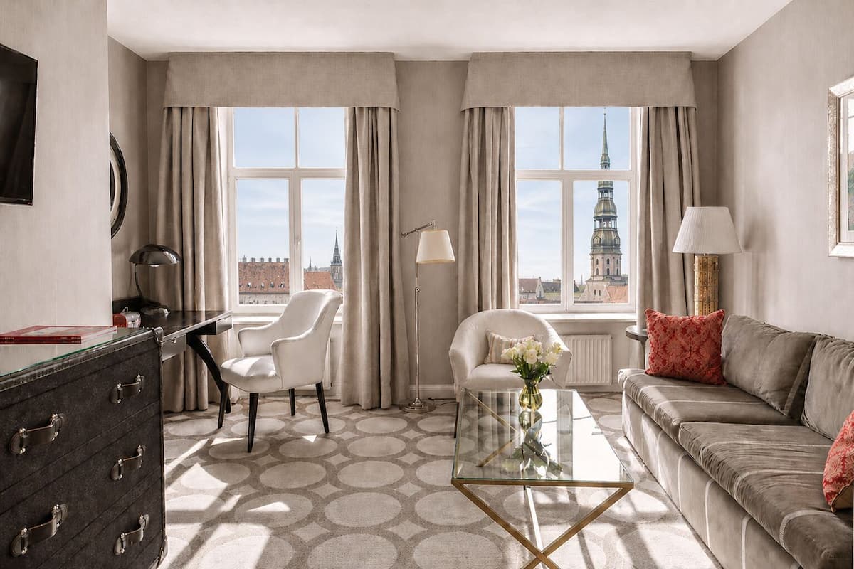 Una habitación de hotel con vistas a la ciudad, un escritorio con lámpara, un sofá y una silla.