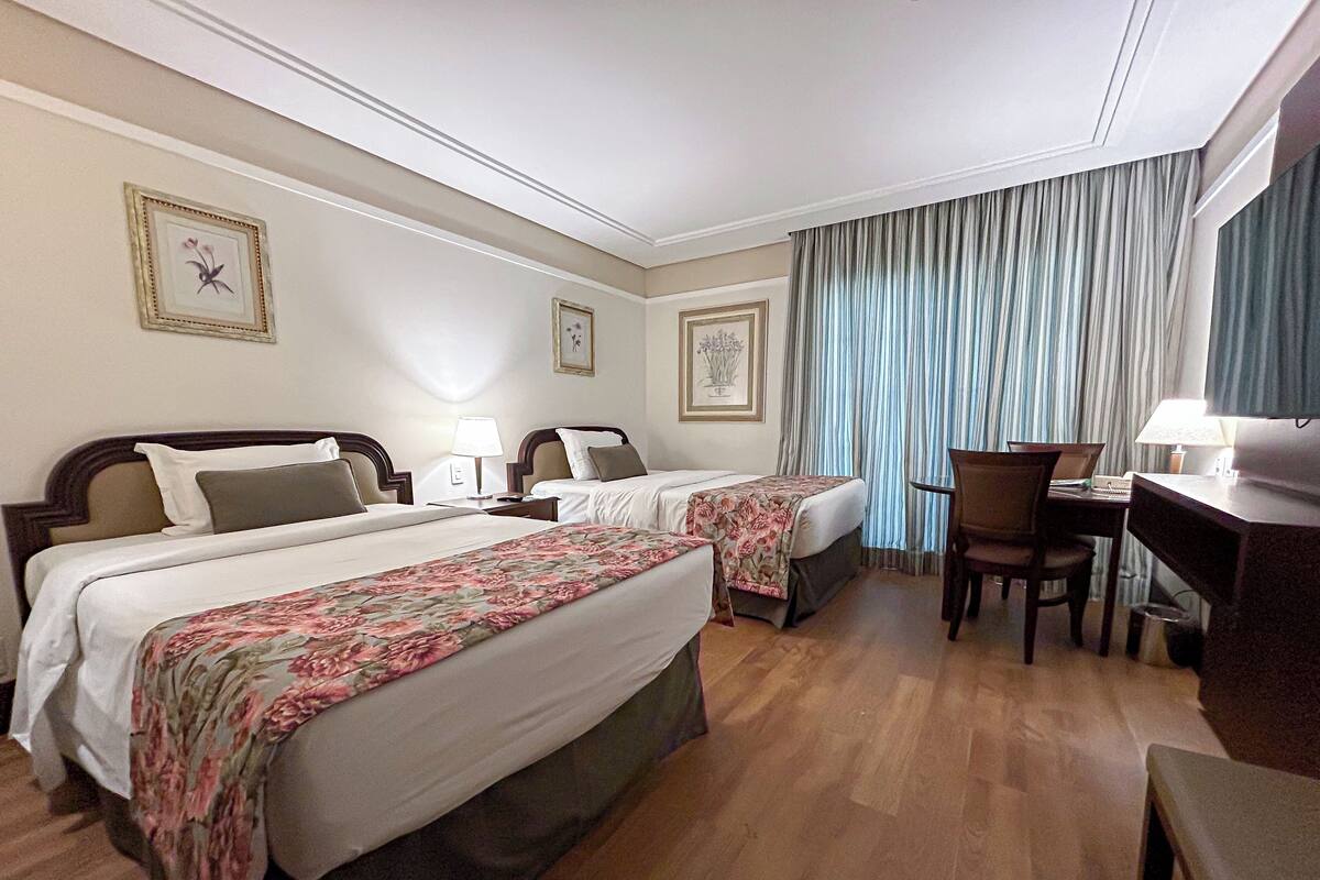 Une chambre d’hôtel avec deux lits, un bureau et une chaise.