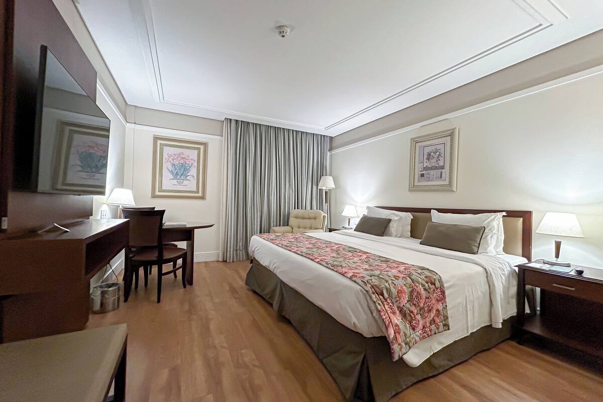 Une chambre d’hôtel comprenant un lit, un bureau, une chaise et deux tables de chevet.