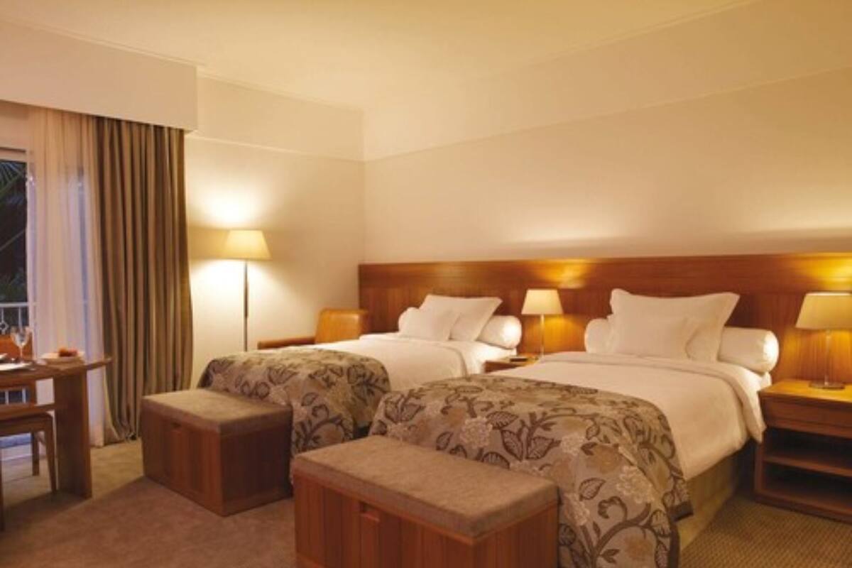 Une chambre d’hôtel avec deux lits, un bureau, une chaise et une petite table.