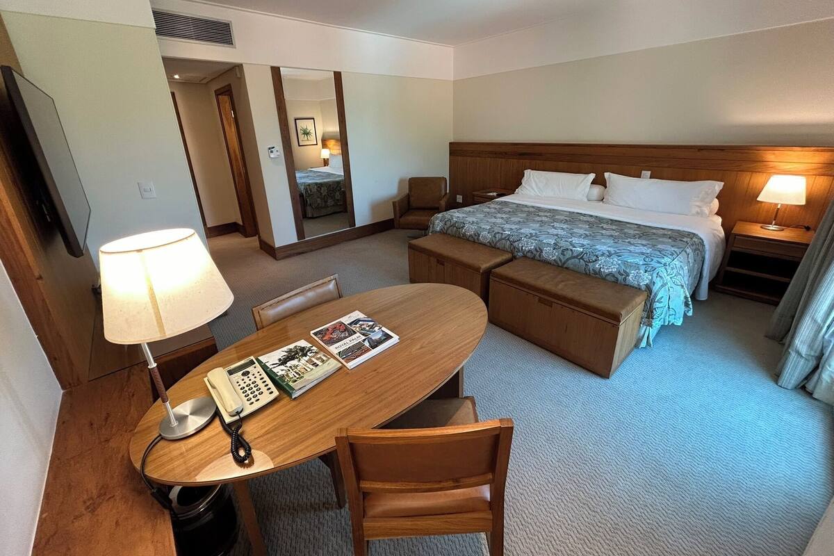 Une chambre d’hôtel comprenant un lit, un bureau avec un téléphone, une chaise, une table de chevet avec une lampe et un miroir.