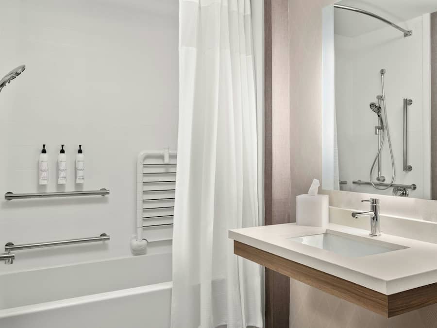 A modern bathroom with a bathtub, shower, and vanity.