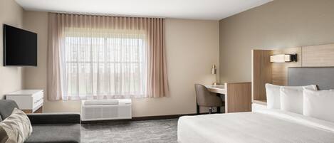A hotel room with a bed, a desk, a chair, a TV, and a window with curtains.