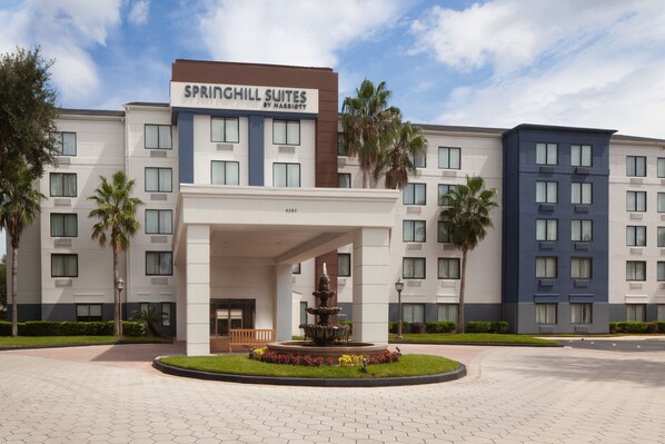 A hotel with a sign reading "SPRINGHILL SUITES BY MARRIOTT" and a fountain in the entrance area.