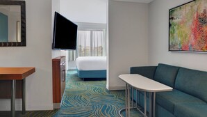 A hotel room with a bed, a TV mounted on the wall, a small table, and a colorful abstract painting. - SpringHill Suites by Marriott Jacksonville (Jacksonville)