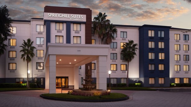 A hotel entrance with a sign reading "SPRINGHILL SUITES BY MARRIOTT," a fountain, and a landscaped area with palm trees. - SpringHill Suites by Marriott Jacksonville (Jacksonville)