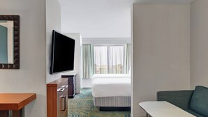 A hotel room with a bed, a TV mounted on the wall, a small table, and a sofa. - SpringHill Suites by Marriott Jacksonville (Jacksonville)