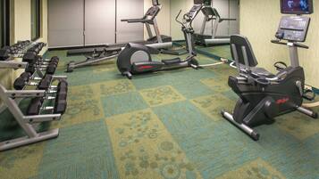 Un gimnasio de hotel con diferentes equipos de ejercicio, incluyendo cintas de correr, elípticas y máquinas de pesas.