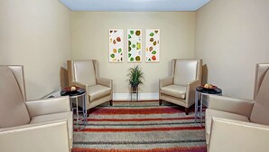 A room with two beige armchairs, a small round table, and a colorful striped rug. There are three framed artworks on the wall. - MainStay Suites Northbrook Wheeling (Wheeling)