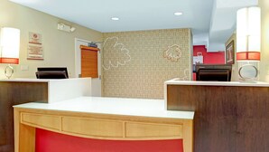 A reception area with a wooden desk, a red cushioned bench, and a patterned wall. - MainStay Suites Northbrook Wheeling (Wheeling)