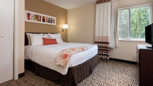 A hotel room with a bed, a desk, a TV, a window with curtains, and a wall with artwork. - MainStay Suites Northbrook Wheeling (Wheeling)