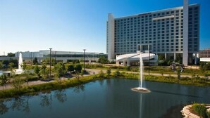 A modern hotel with a large building, a fountain, and a landscaped area with a pond. - MainStay Suites Northbrook Wheeling (Wheeling)