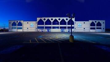 Un ampio edificio moderno con una facciata simmetrica, diversi accessi e un parcheggio di fronte.