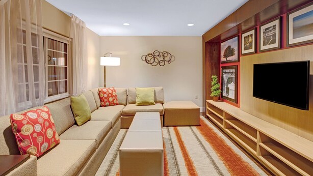 A modern living room with a sectional sofa, a flat-screen TV, and a decorative wall with framed pictures. - MainStay Suites Northbrook Wheeling (Wheeling)