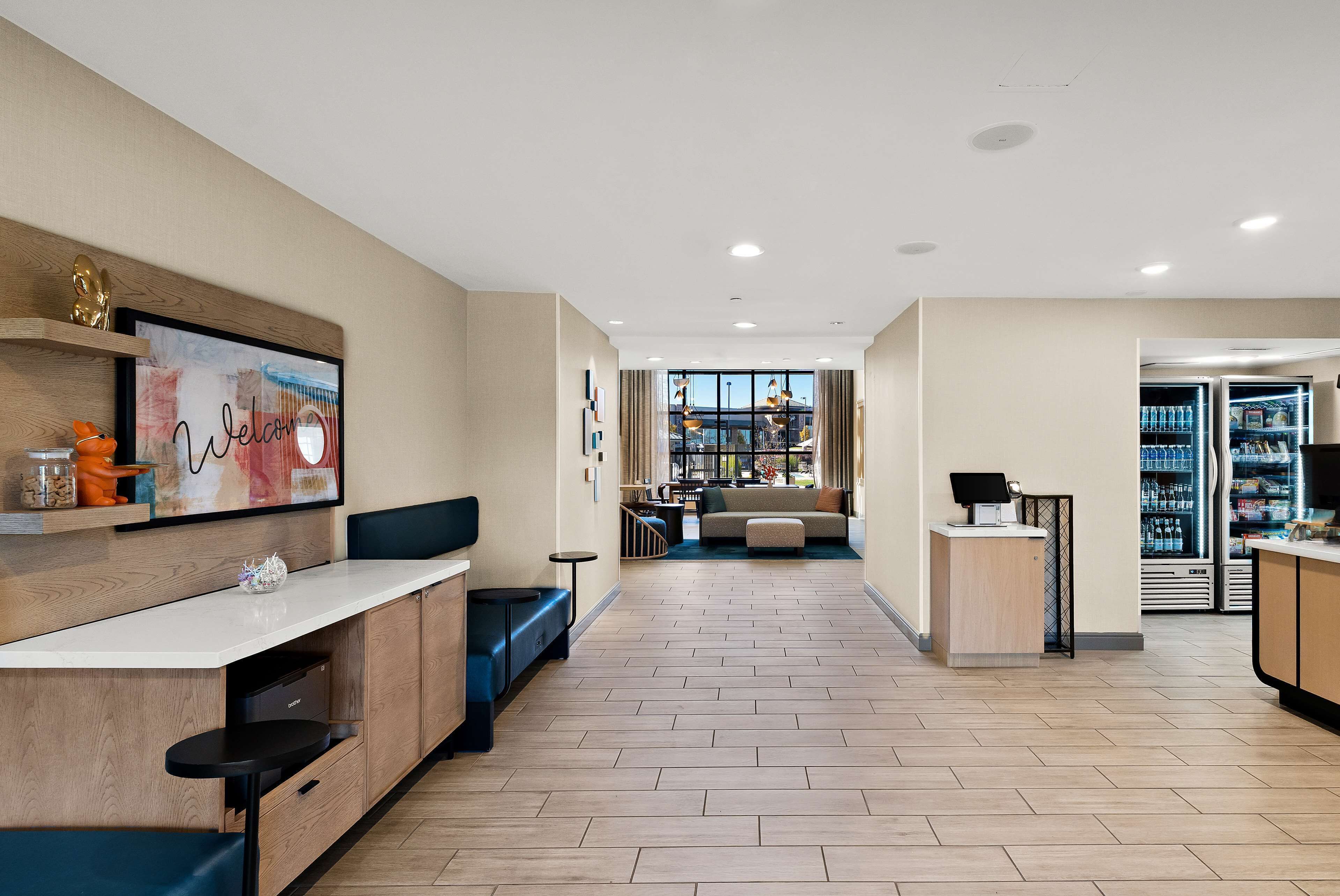A modern kitchen with a white countertop, wooden cabinets, and a seating area with blue cushions.