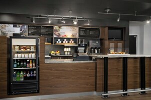 Un moderno bar-bistrot con una vetrina refrigerata per bevande, una postazione caffè e una lavagna per il menu.