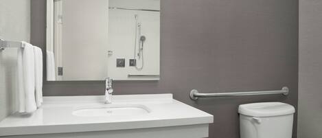 Een badkamer met een witte wastafel, een spiegel, een toilet en een douche.
