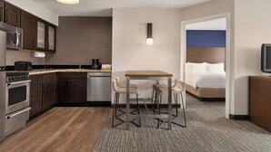 Ein kompaktes Hotelzimmer mit Küchenzeile, einem Bett, einem Fernseher und einer kleinen Essecke.