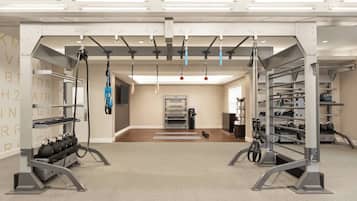 A modern gym with ceiling-mounted exercise equipment, kettlebells, and a wall-mounted oven.