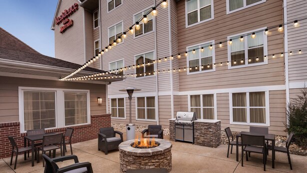 Eine Hotelterrasse mit Sitzgelegenheiten im Freien, einem Steinkamin und Lichterketten.