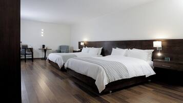 Quarto de hotel com uma cama grande, mesas de cabeceira, uma cadeira e uma escrivaninha.