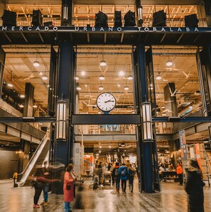 An indoor space with a large clock, escalators, and a sign reading 'MERCADO URBANO TOBALABA'. - MR Hotel (Santiago)