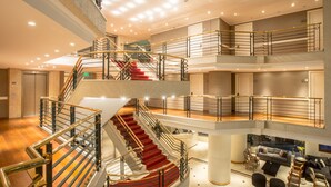Un interior de varios niveles con una escalera central, múltiples zonas de estar y un techo alto con iluminación empotrada.