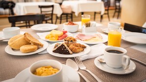 Una mesa de desayuno con diversos alimentos, como pasteles, huevos y jugo.
