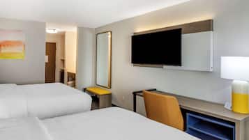 Habitación de hotel con dos camas, un escritorio, una silla, un televisor, un espejo y una lámpara.
