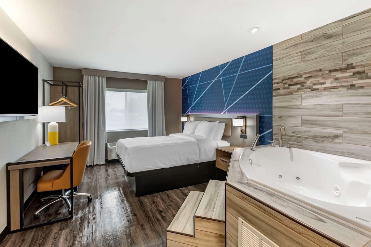 Une chambre d’hôtel moderne équipée d’un lit, d’un bureau, d’une chaise et d’une grande baignoire.