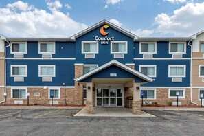 A Comfort Inn hotel with a blue and beige exterior, multiple windows, and a parking lot.