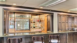 Uma área de bar com balcão, banquetas e uma variedade de garrafas de bebidas.
