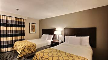 A hotel room with two beds, a nightstand with a lamp, a framed picture on the wall, and striped curtains.