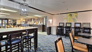 Um saguão de hotel com área de bar, assentos e máquinas de venda automática.