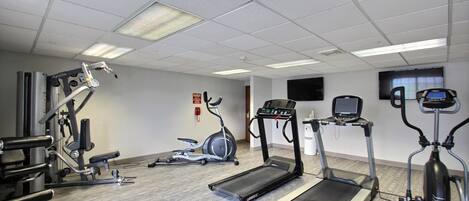 Un gimnasio con cintas de correr, elípticas y equipo de levantamiento de pesas.