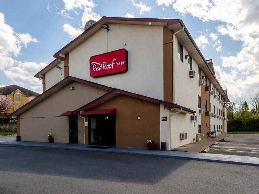 A Red Roof Inn with a red awning, a clear sky, and a parking lot.