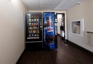 A hallway with vending machines, including a Pepsi dispenser, and a coat rack with a dog. - Red Roof Inn Culpeper (Culpeper)
