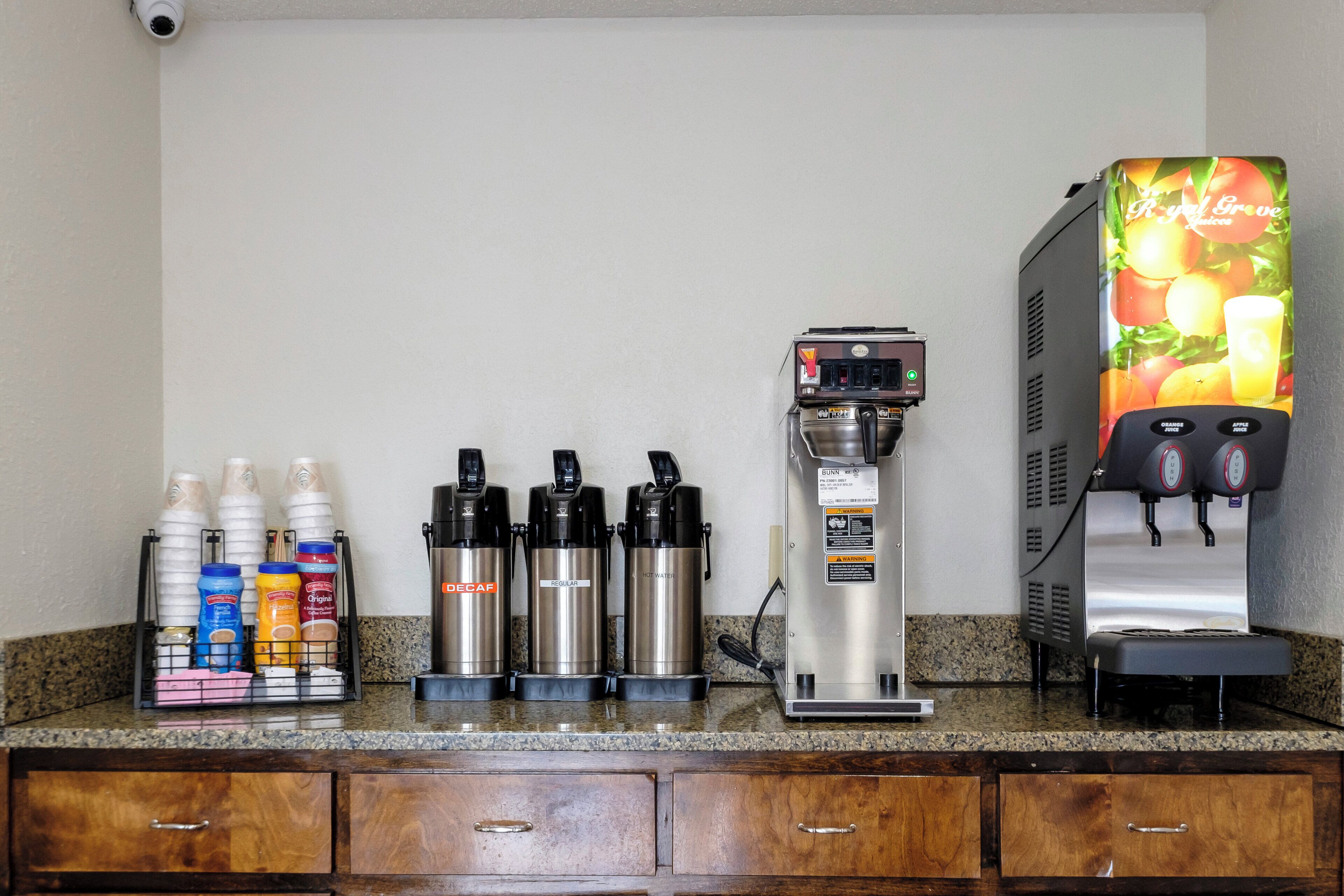 A coffee station with a coffee machine, decaf and regular options, and a juice dispenser.