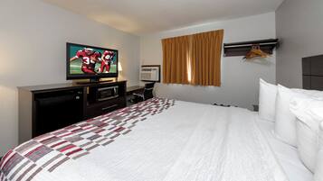 Una habitación de hotel con cama, televisión, escritorio y aire acondicionado instalado en la pared.