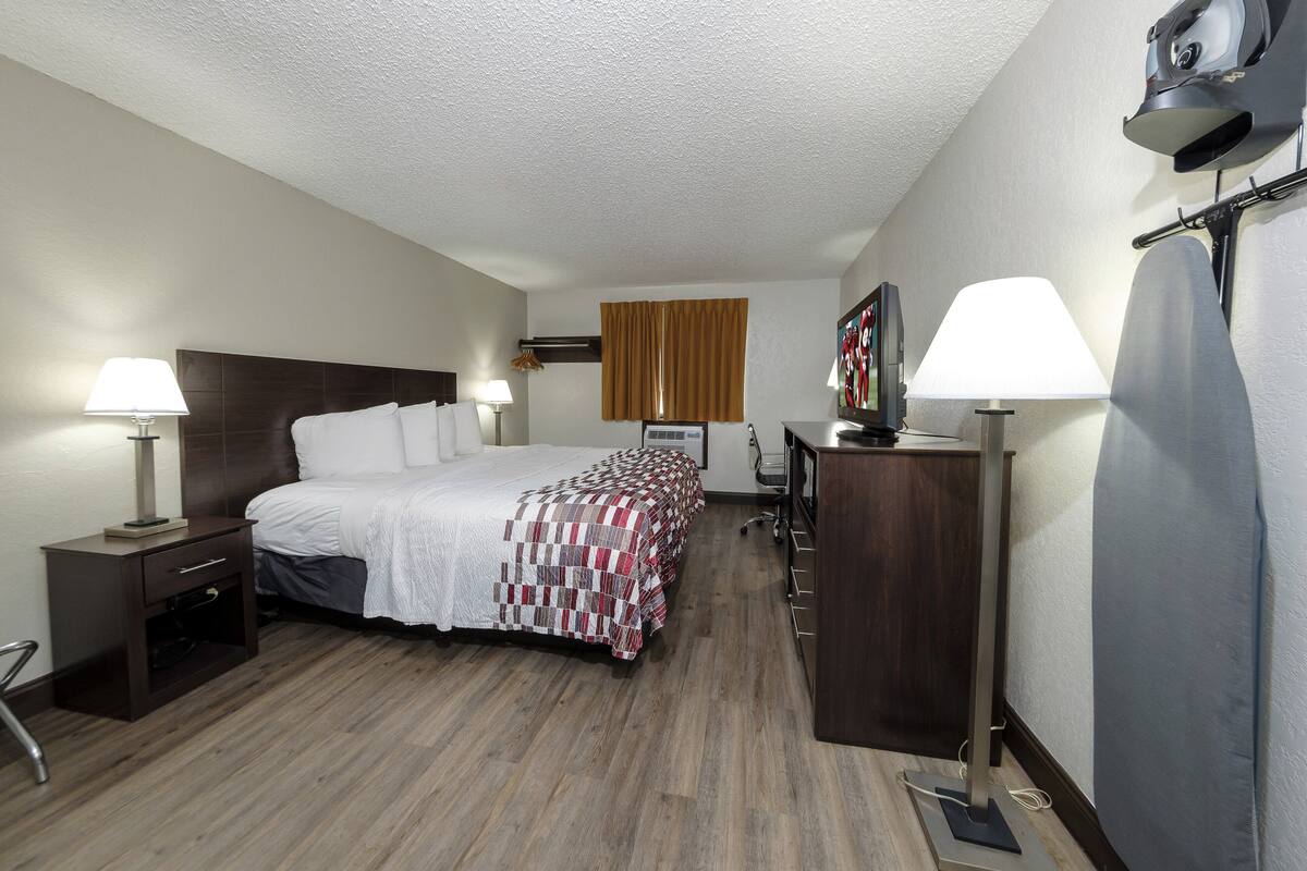 A hotel room with a large bed, two bedside tables with lamps, a desk, and a wardrobe.