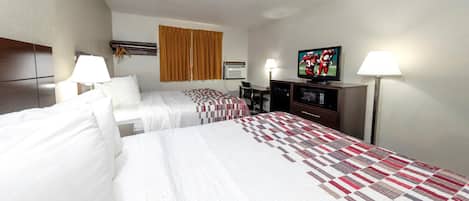 A hotel room with two beds, a television, a desk, and a window with curtains.