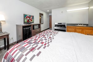Habitación de hotel con cama, televisión, microondas, estufa y kitchenette.