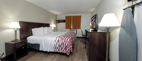 A hotel room with a bed, bedside tables, a desk, a chair, a TV, and a wardrobe.