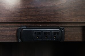 A dark wooden panel with a black electrical outlet box containing three sockets and a USB port. - Red Roof Inn Culpeper (Culpeper)