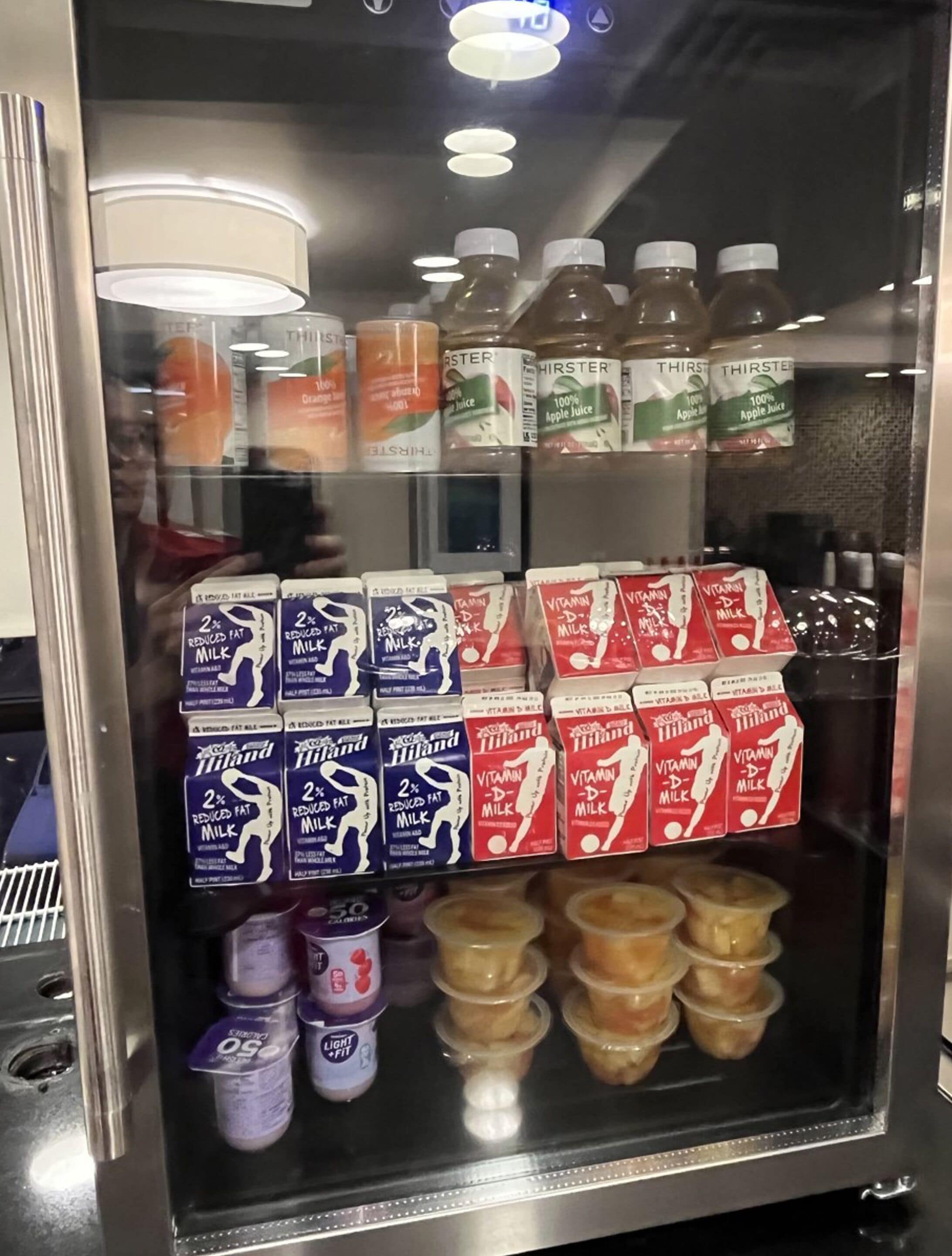 A refrigerated beverage dispenser with various drinks including apple juice, milk, and yogurt.