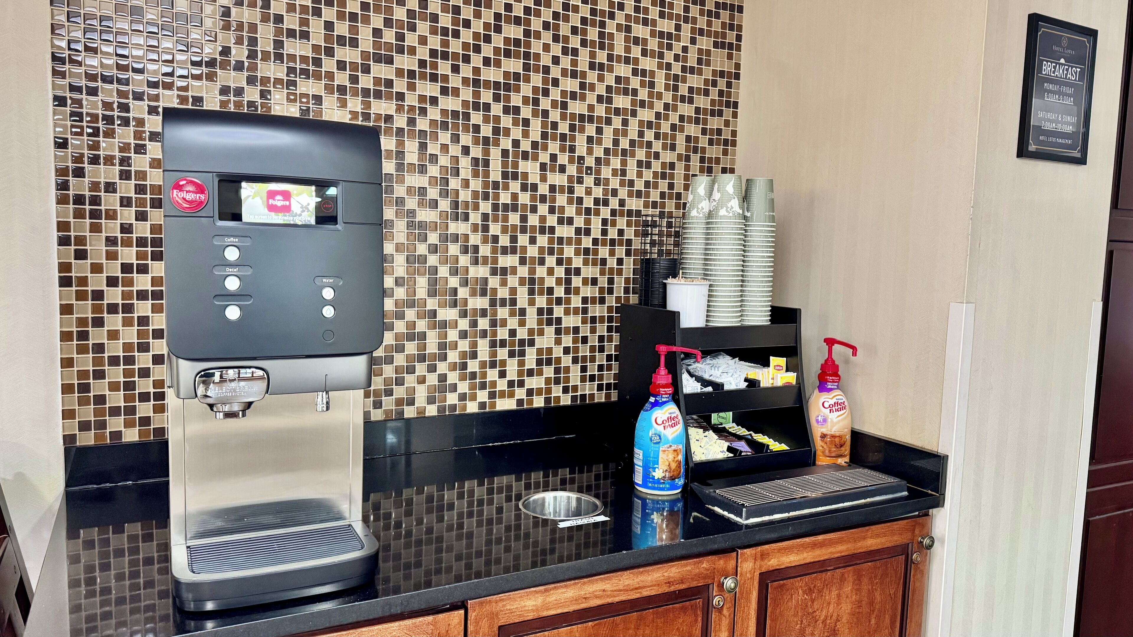 Una estación de café con una cafetera, una botella de leche para café y un dispensador de crema.